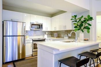 Well-appointed kitchen with quartz countertops & glass backsplash